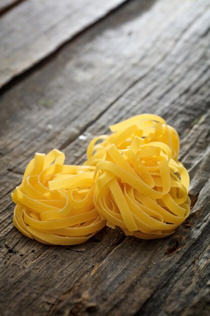 Tagliatelle pasta nests set on wooden surface