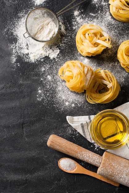 Tagliatelle pasta ongekookt, spaghetti achtergrond, zwarte textuur, bovenaanzicht, kopie ruimte, verticaal maken