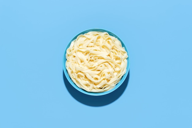 Tagliatelle pasta top view Cooked noodles in a bowl on a blue background