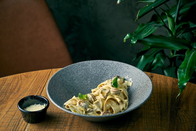 Паста тальятелле с белым соусом и лесными грибами в тарелке. итальянская еда