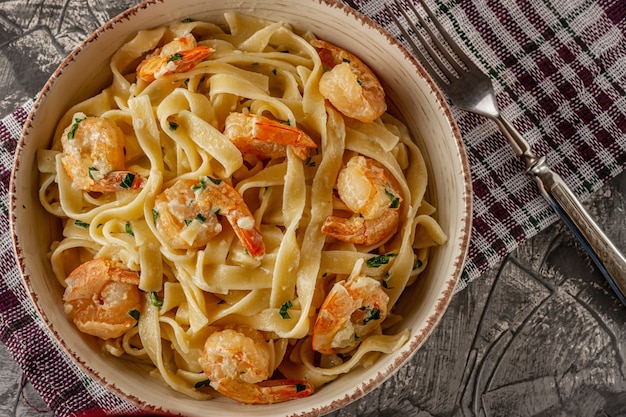 Tagliatelle with prawns and parsley on a gray table