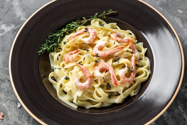 Tagliatelle with shrimps and thyme, fettuccine pasta. Italian food. recipe background. Close up.