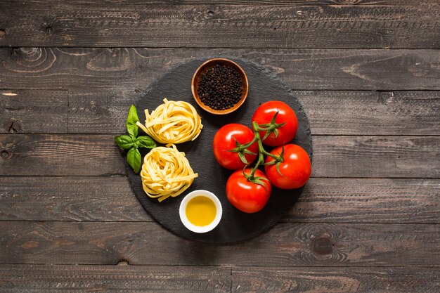 Foto tagliatelle al pomodoro e basilico, fatte in casa, su uno sfondo di legno.