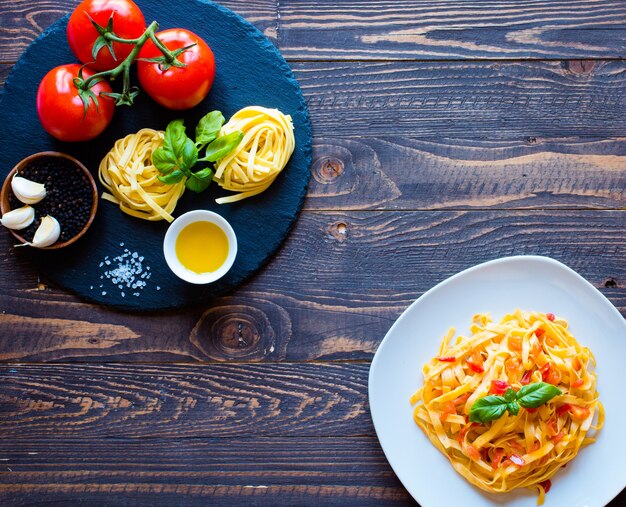 토마토와 바 질, 나무 배경에 집에서 만든 Tagliatelle.