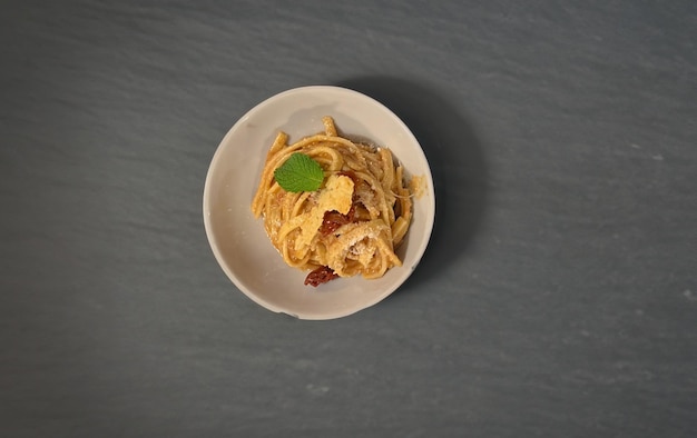 Foto tagliolini basilico pomodoro secco e pecorino su piatto bianco