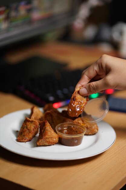 Photo tahu walik or fried tofu with whitr plate and a hand on a computer table