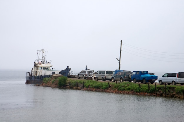 Tail of cars to ferry on pier