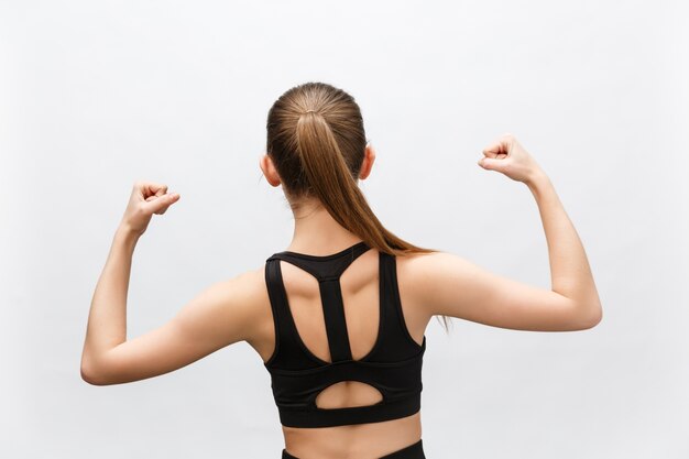 Taille-up shot van sportieve vrouw steekt hand op om haar spieren te tonen