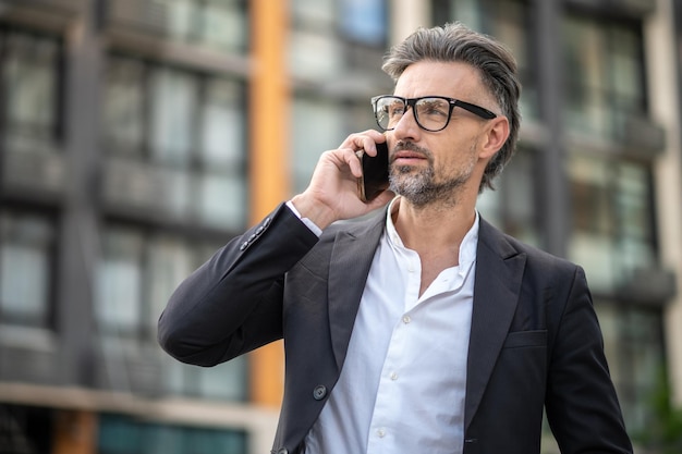 Taille van een stijlvolle zakenman die aan de telefoon praat