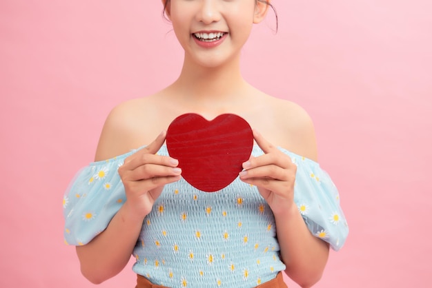 Tailleportret van een mooie Aziatische vrouw die wegkijkt met een brede glimlach terwijl ze de Valentijnsdagkaart in handen houdt