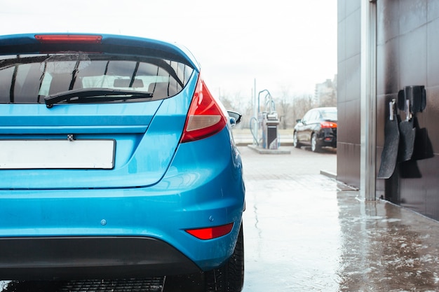 Taillight of a blue hatchback standing at a car wash