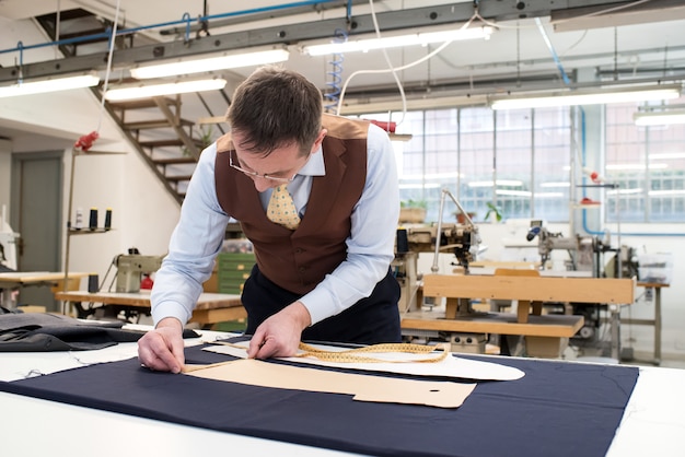 Tailor laying out paper patterns on blue fabric