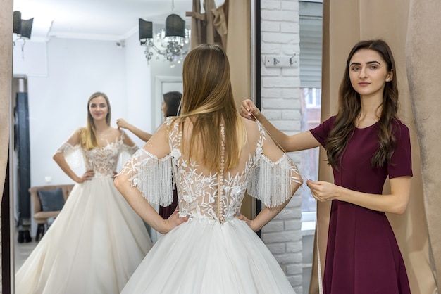店内の花嫁のウェディングドレスの測定を調整する