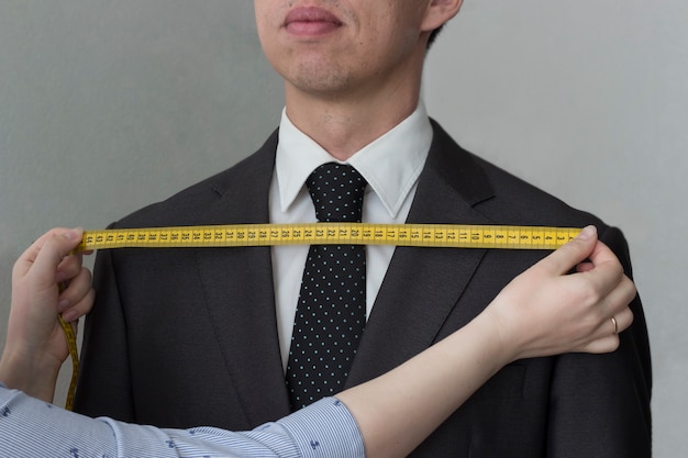 Tailor removes the measurements from the jacket of a man