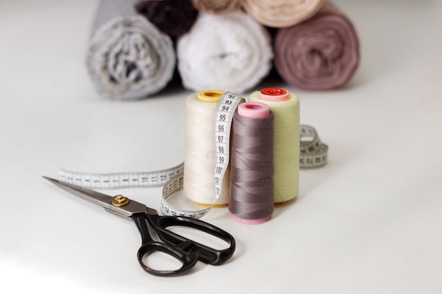 Tailor scissors with thread skewers and cloth on the background on the table