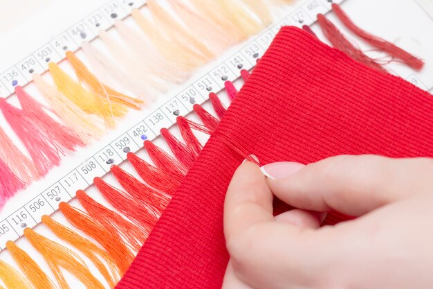 Tailor seleziona il colore del filo nel catalogo per il tessuto rosso. negozio di atelier di tessuti e accessori.