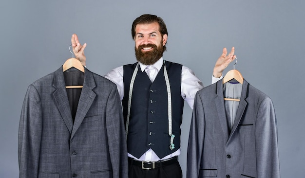 Photo tailor sewing handsome bearded fashion man in classical costume suit man in custom suit presenting expensive tailored tuxedo man clothing in boutique man with suit tailor in his workshop