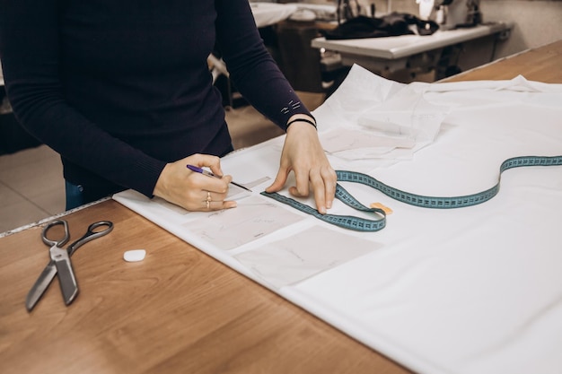 Photo tailor sews clothes a woman dressmaker makes patterns in her atelier