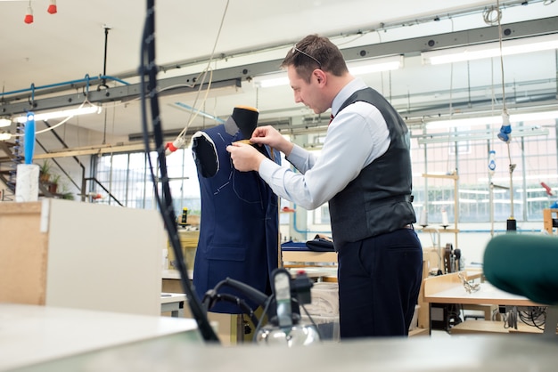 Tailor standing working on a blue jacket