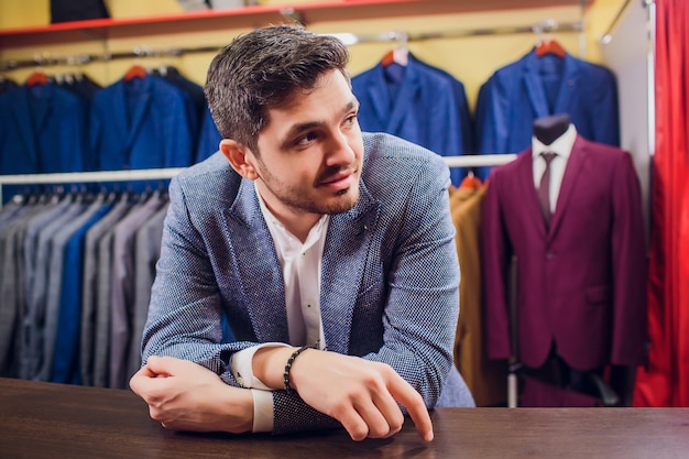 Sarto, sartoria. abito da uomo, sarto nel suo laboratorio. abiti da uomo eleganti appesi in fila. abiti classici da uomo di lusso su rack nell'elegante boutique da uomo. sbadiglia stanco di scegliere