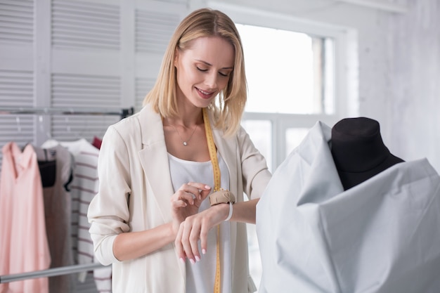 仕立てのプロセス。見下ろしながらピンを取るうれしい女性の仕立て屋