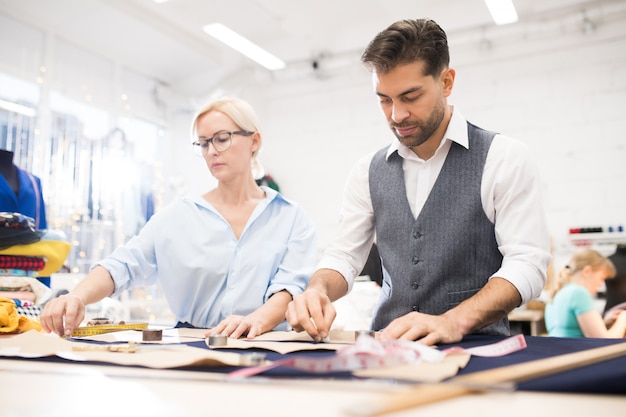 Foto sarti che lavorano al tavolo in atelier studio