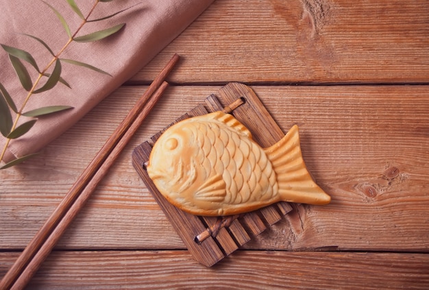 Taiyaki Japanese street food fish-shaped sweet filling waffle on wooden table.