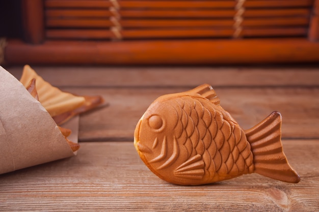 Taiyaki Japanese street food fish-shaped sweet filling waffle on wooden table.