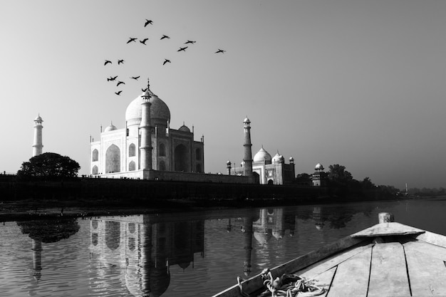 Taj Mahal reflected in Yamuna River view from wooden boat in black and white.