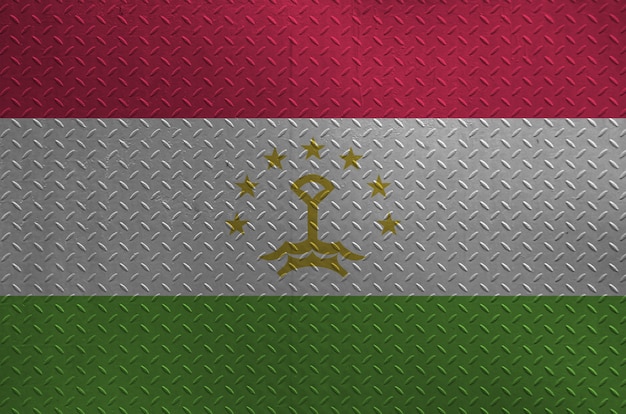 Tajikistan flag depicted in paint colors on old brushed metal plate or wall closeup. Textured banner on rough background