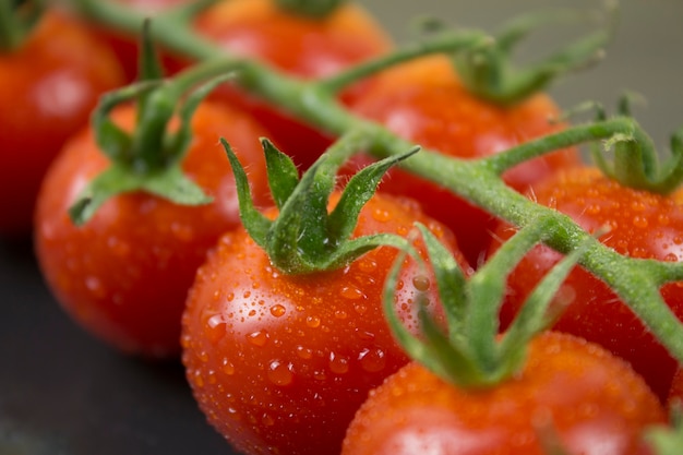 Tak van kleine rode tomaten op zwarte stenen achtergrond Close up