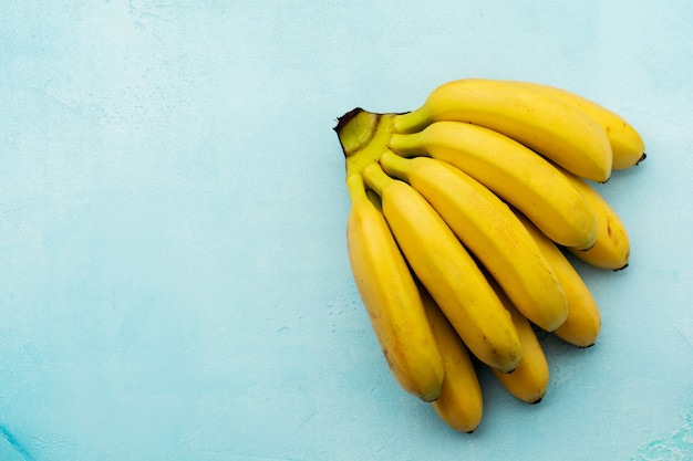 Tak van verse babybananen op turkoois betonnen ondergrond. Bovenaanzicht.