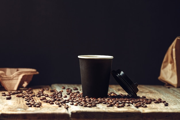 Take away coffee cup and coffee beans on wooden table