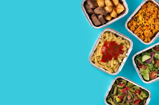 Take away healthy food in foil boxes on blue table