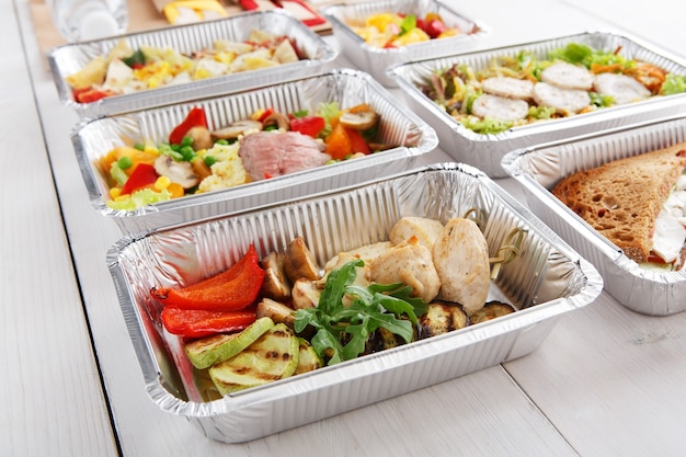 Take away of natural organic food in foil boxes. meat and vegetable salads. Top view, flat lay.