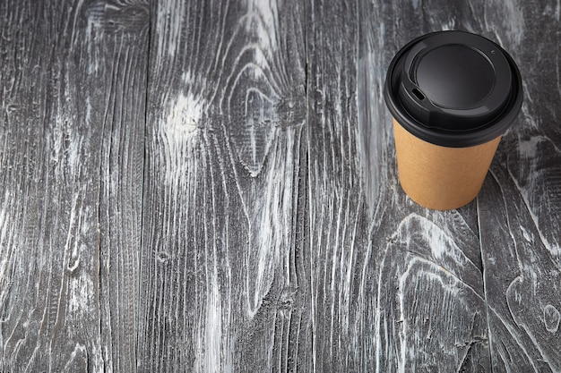Foto porta via la tazza di caffè di carta su fondo di legno grigio