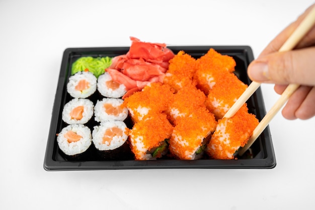 Involtini di sushi da asporto in un contenitore di plastica, california, salmone maki roll, zenzero rosa, wasabi. concetto di consegna di sushi