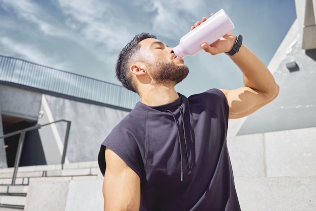 Take breaks so you dont overwork yourself. Shot of a sporty young man drinking water while exercising outdoors.