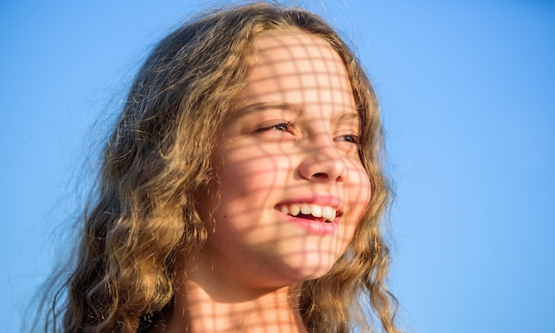 Take care Uv filter sunscreen Summer care Sunscreen concept Child pleased with warm sunlight looks relaxed blue sky background Take care skin put sunscreen cosmetics Girl kid relaxing outdoors