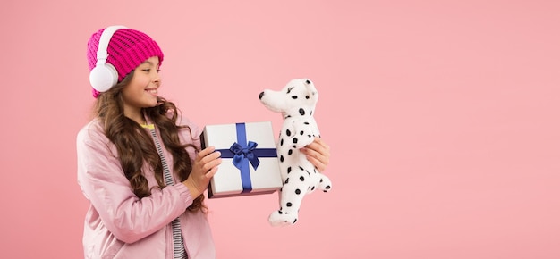 Take favorite toy with you happy childhood concept best gifts\
for teen girls stylish schoolgirl play with dog toy and hold gift\
box girl little fashionable cutie with headphones carry soft\
toy