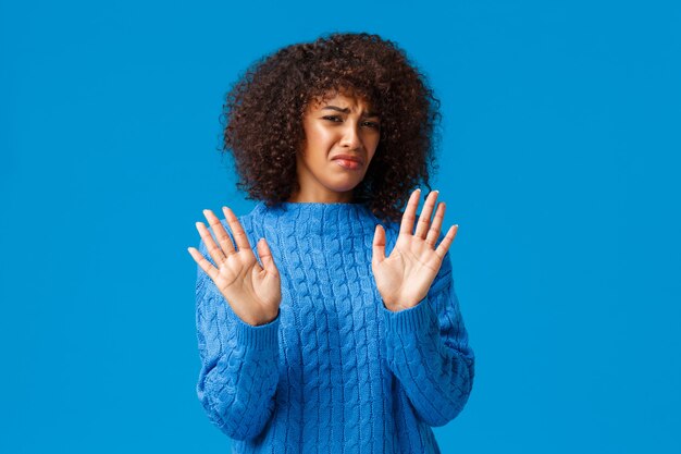 Foto portalo via da me. disgustata e scontenta, sciocca ragazza afro-americana con taglio di capelli afro, stringe la mano in segno di rifiuto, esprime riluttanza e avversione