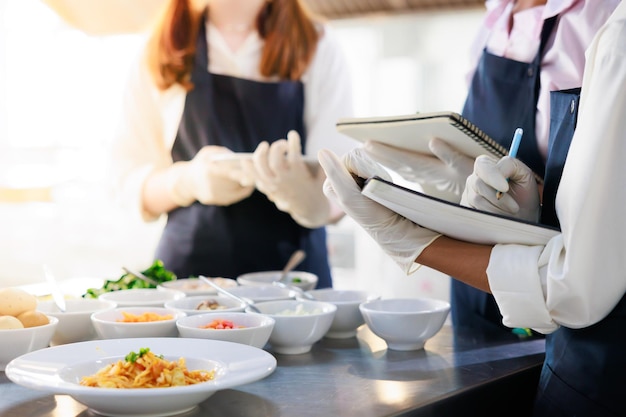 本に注意してください幸せな若い女性の多民族の学生の料理教室料理教室グループは料理学校で料理教室に焦点を当てています