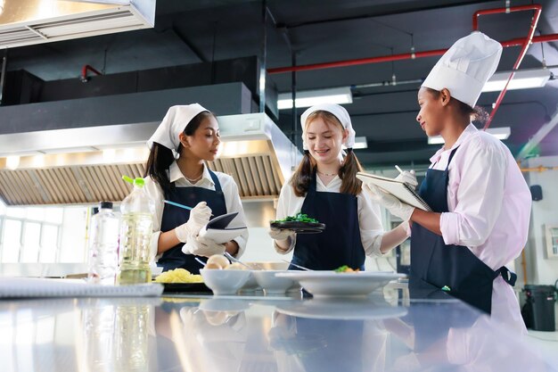 Take note on book Cooking class culinary classroom group of happy young woman multiethnic students are focusing on cooking lessons in a cooking school