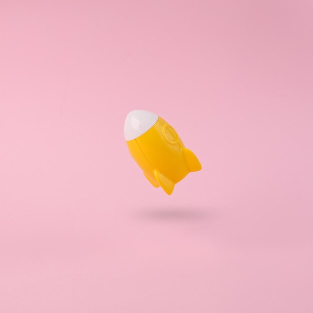 Foto decollare una navetta spaziale o un razzo giallo su uno sfondo rosa con ombre minimalismo concettuale pop idea fresca o startup