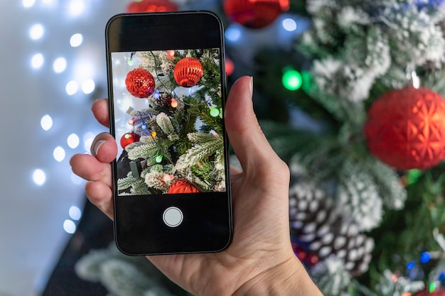 Take a vivid beautiful photo of the Christmas tree. Bloggers shoot for social media. Beautiful Christmas tree in the snow.