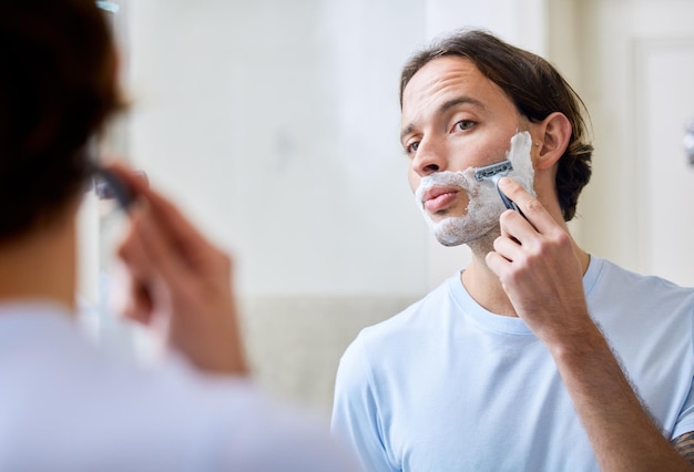 Не торопитесь, чтобы предотвратить несчастные случаи Снимок молодого человека, бреющегося утром