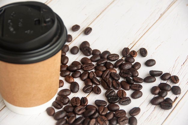 Takeaway coffee cup surrounded with coffee beans with customizable space for text or ideas Copy space and coffee concept