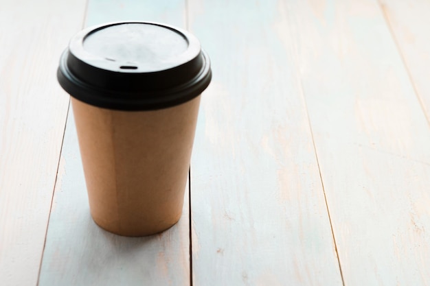 나무 바탕 위의 테이크아웨이 커피 컵