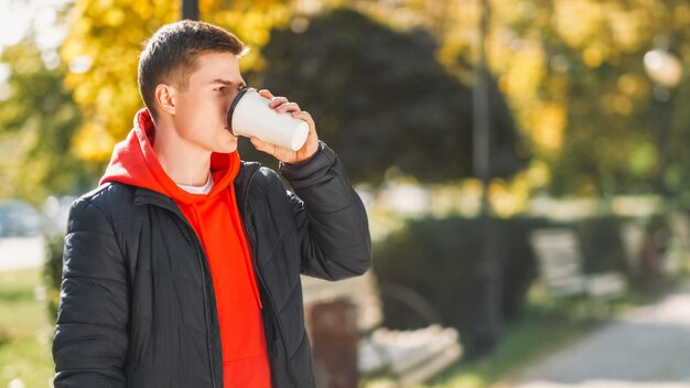 ストリートレートレジャー 休憩 晴れた秋の自然を楽しむ男性 温かい飲み物を飲む