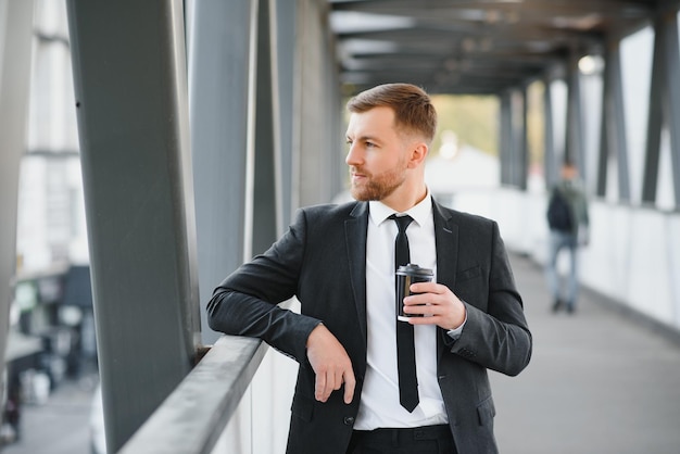 Takeaway coffee Walk and enjoy fresh hot coffee Waiting for someone in street Man bearded hipster drink coffee paper cup Businessman well groomed enjoy coffee break outdoors urban background